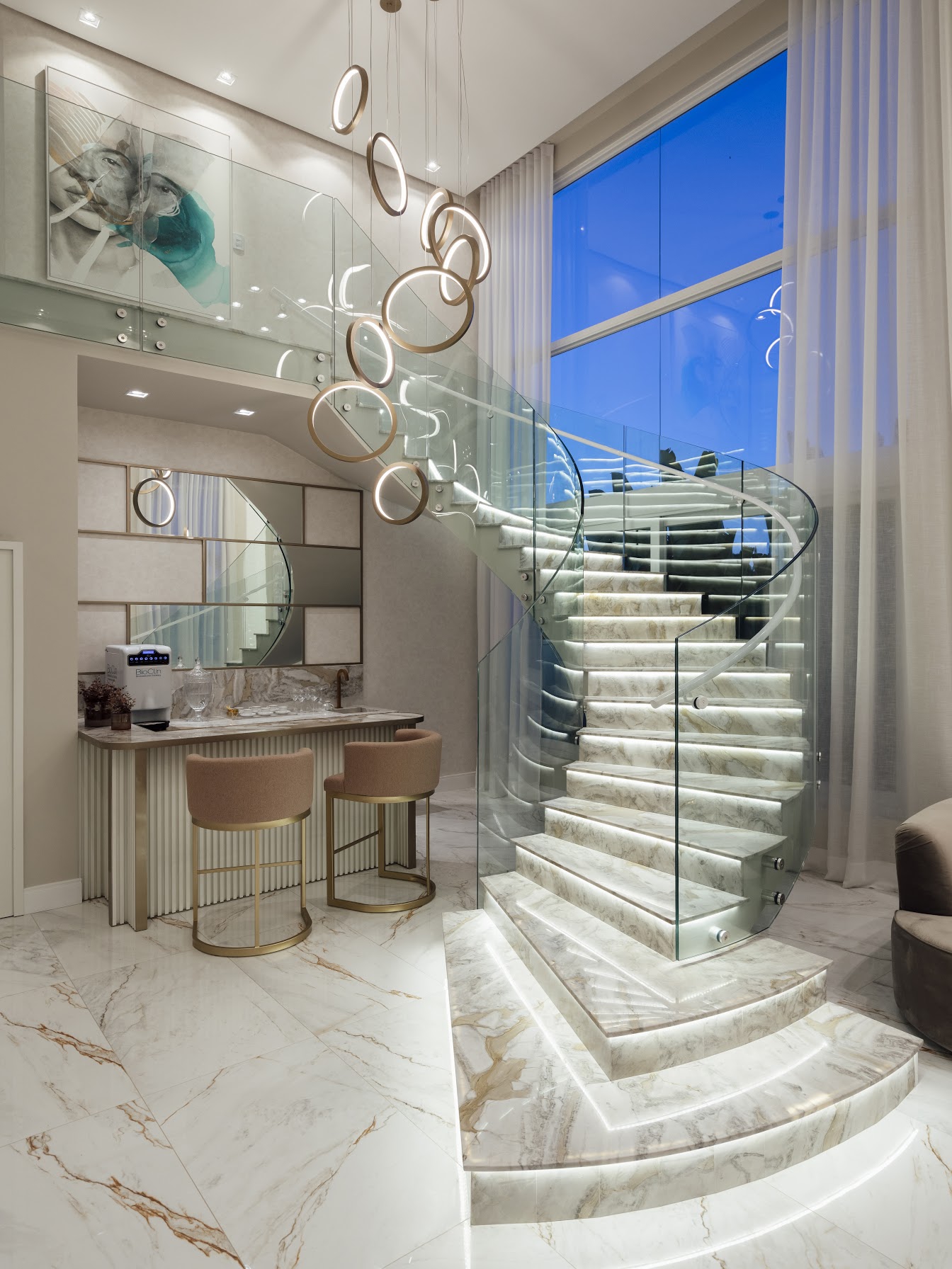 Escada curva em mármore e lustre de anéis dourados